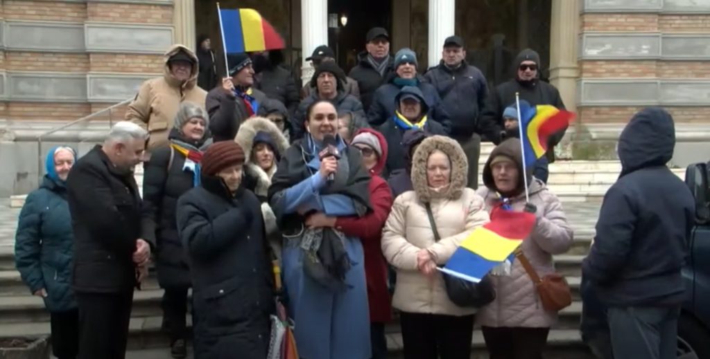 Pe scările Arhiepiscopiei Tomisului, marți dimineață, un grup restrâns de susținători ai fostului candidat la alegerile prezidențiale Călin Georgescu s-a adunat pentru a-și arăta sprijinul