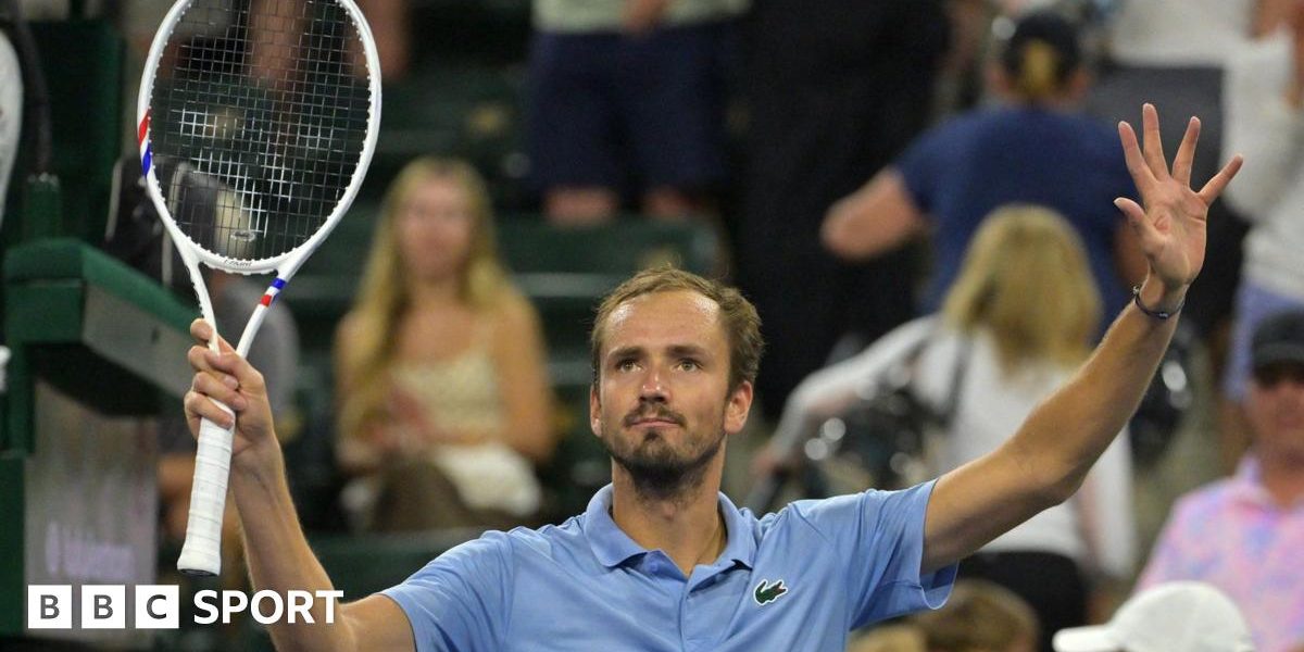 Daniil Medvedev holds up a tennis racquet
