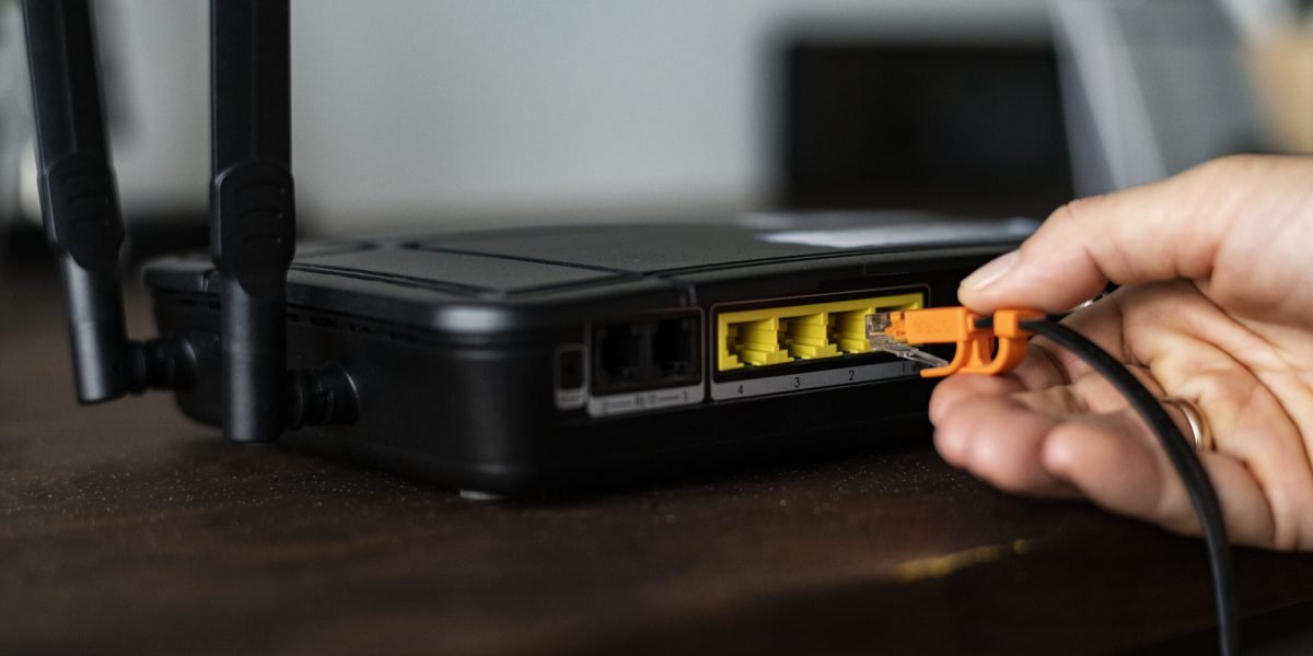 man-plugging-ethernet-cable-wireless-router-1-scaled.jpg - StiriAlese