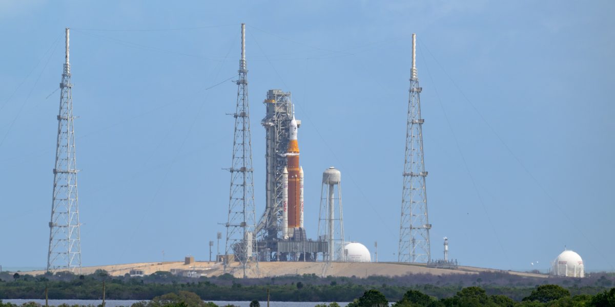 Image shows the orange core stage of the NASA’s Space Launch System (SLS) rocket with the white spacecraft on top making up of the Orion spacecraft at NASA's Kennedy Space Center in Florida.