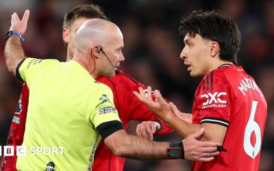 Referee Paul Tierney speaks with Lisandro Martinez of Manchester United after showing him a red card for pulling the hair of Dominic Calvert-Lewin of Leeds United