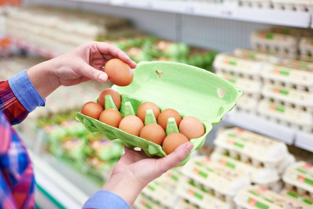 Image text: O imagine cu sute de ouă într-o cutie de carton, la un supermarket